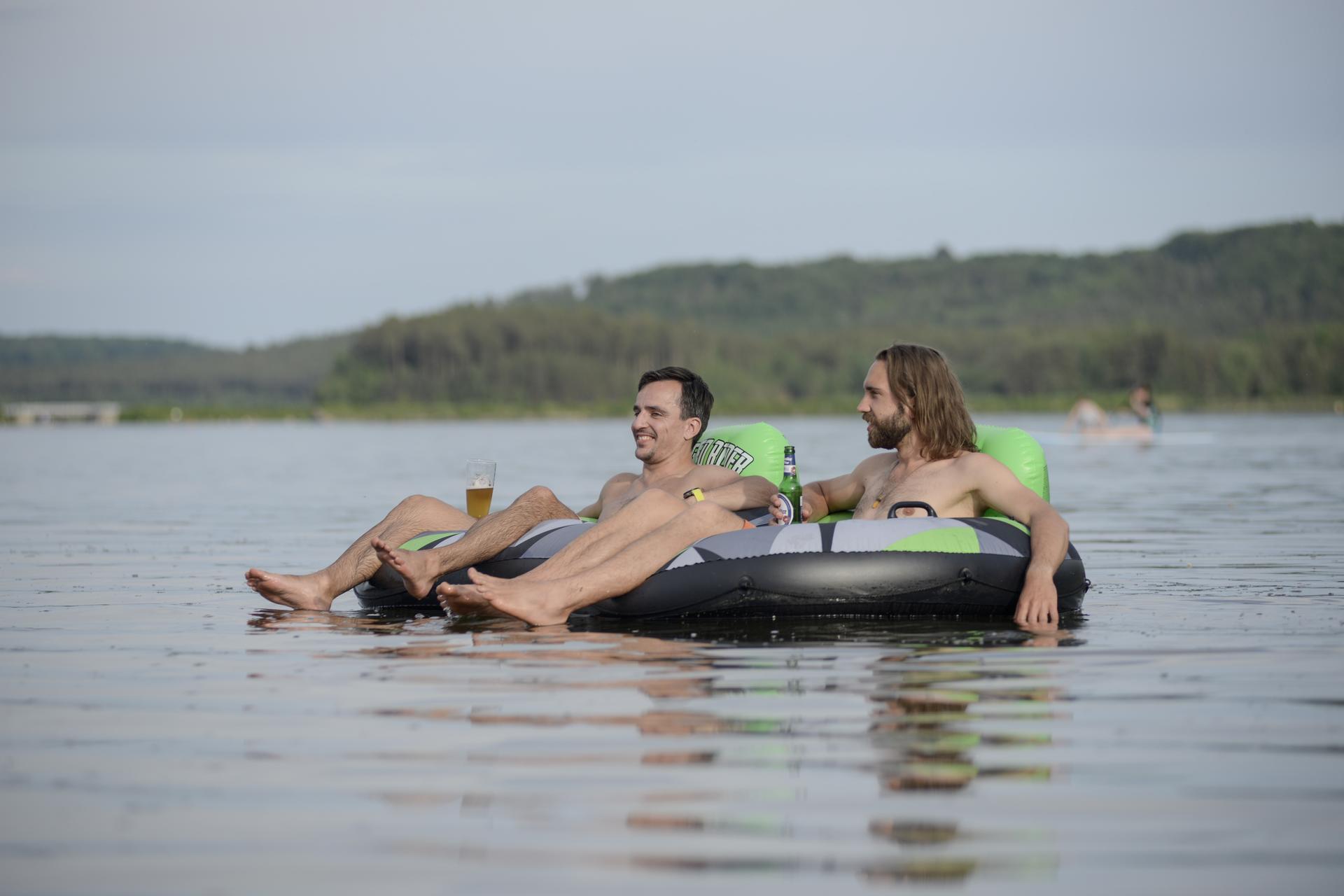 Zwei Männer auf einem Schlauchboot stoßen mit Bier auf einen gelungenen Tag im Bayern Wakeboard Camp an  – APACAMPA Reisen