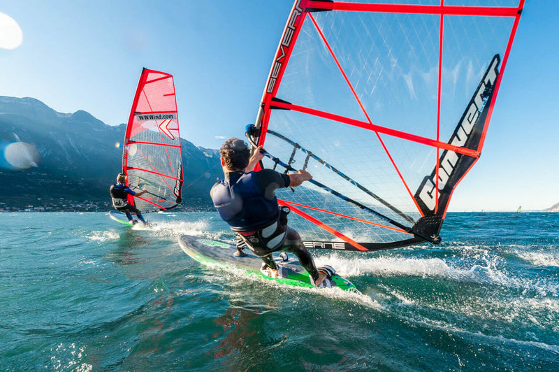 Professionelle Windsurfer nutzen die starken Böen vor einer traumhaften Bergkulisse in Italien im Gardasee Windsurf Camp – APACAMPA Reisen