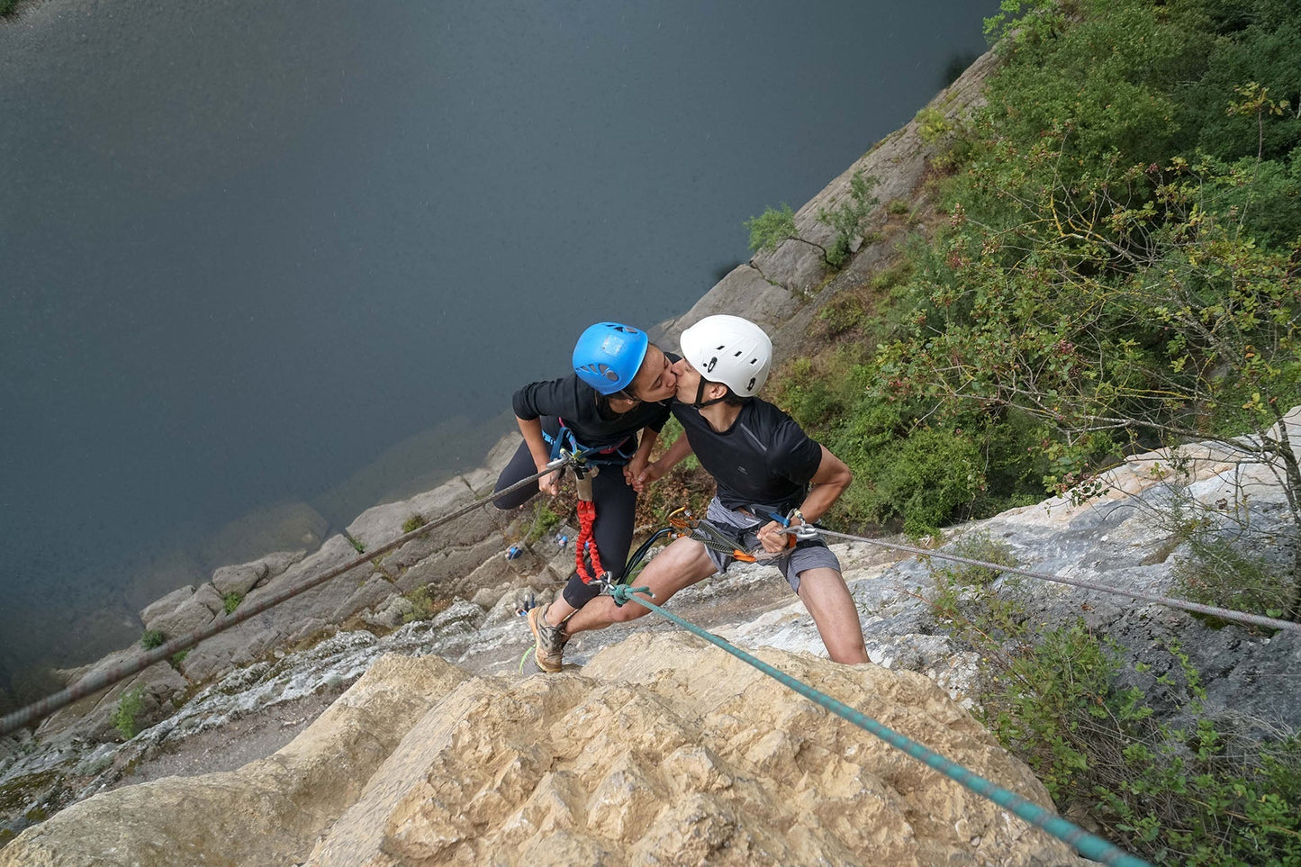EIn verliebtes Pärchen küsst sich beim Klettern im Kletterstig über einem See im Ardèche Special Camp – APACAMPA Reisen